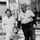 Lauretto "Laura" and Gaetano "Joe" Ionnone (Reno) with one of their grandchildren, in front of their store at 4th Avenue and C Street, Anchorage.