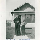 Father O’Flanagan standing before the Catholic rectory next to Holy Family Church in Anchorage in 1941.  The name of the boy is unknown.